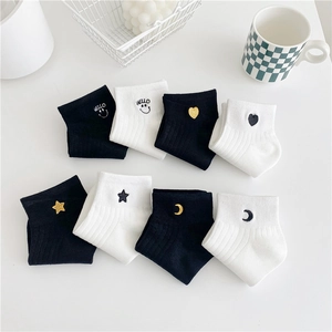 Detail of 8 pairs black and white cotton socks with embroidered patterns on white table