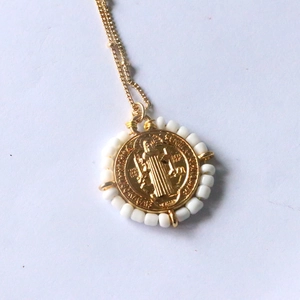 Detail of gold Virgin Mary pendant with white beads and dainty link chain jewelry