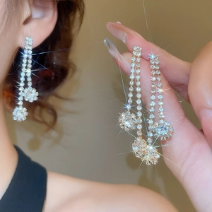 Close-up of golden tassel earrings featuring sparkling zircons and large diamond pendants