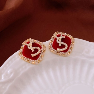 Détail de boucles d'oreilles carrées en or avec cœur rouge et accents de nœud en diamant