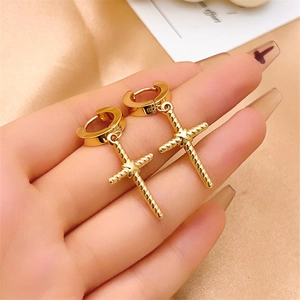 Close-up of polished gold cross earrings with hoop clasp held in hand by a model