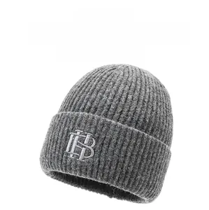 Gros plan du bonnet en tricot gris avec texture à rayures verticales et broderie argentée