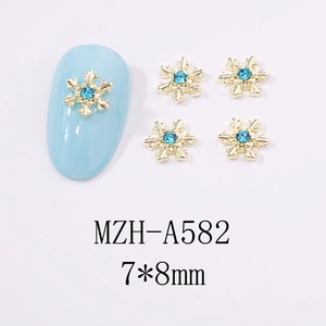 Vue détaillée des bijoux d'ongles flocons dorés 7x8mm avec strass bleus pour manucure d'hiver