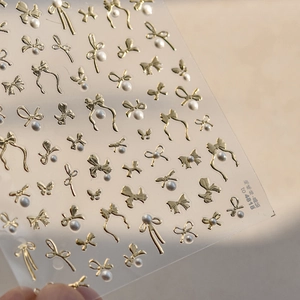 Detailed view of TO-4818 golden 3D bow nail art stickers with elegant white pearl accents