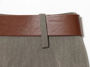 Détail de la ceinture en cuir marron et du tissu en sergé gris à la taille du pantalon