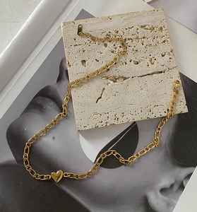 Détail du collier cœur plaqué or 18 carats avec maille Figaro sur support en pierre
