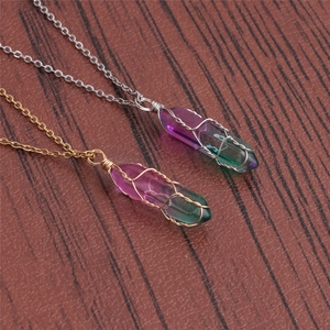 Detail of wire-wrapped hexagonal crystal pendants with purple-green gradient on wood