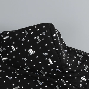 Detailed view of sheer black mesh fabric with silver rhinestones on a long sleeve dress