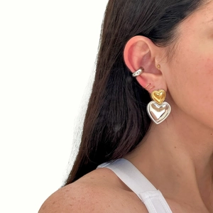 Minimalist gold and silver mixed metal heart drop earrings worn by a model on white background