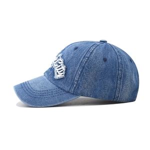 Close-up of white 3D City embroidery on washed blue denim baseball cap showing fabric texture