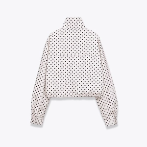 Chaqueta de cuello alto con lunares negros sobre fondo blanco y dobladillo elástico