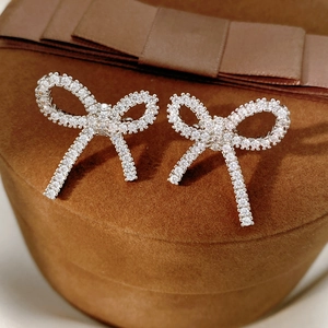 Macro shot of silver bow clip-on earrings with pavé zircon on dark velvet box