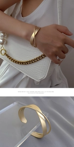 Detailed view of a golden minimalist double-layer crossover bangle on model and matte surface