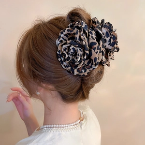 Détail d'une grande pince à cheveux fleur à motif léopard portée pour un look élégant