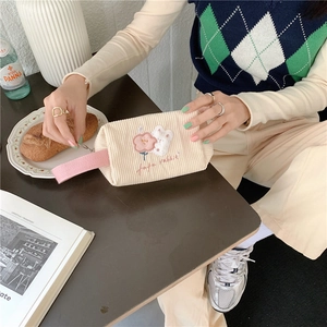 Detail der süßen Hasen-Blumen-Stickerei auf beige Kord-Kosmetiktasche für Reisen