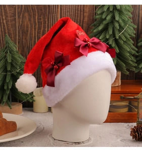Detail of red velvet Christmas hat with white plush trim and red festive bow decorations