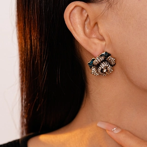 Vintage floral stud earrings with blue enamel and rhinestones on gold base worn by model