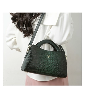 Detail of crocodile embossed dark green tote bag with golden V logo and leather texture