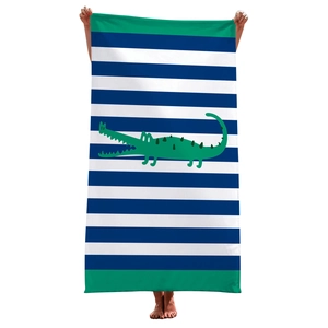 Close-up of beach towel with blue stripes and a large green cartoon crocodile print