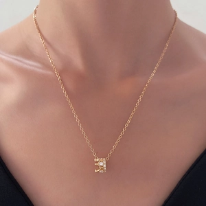 Close-up of a golden crown pendant with sparkling zircons on a delicate chain necklace