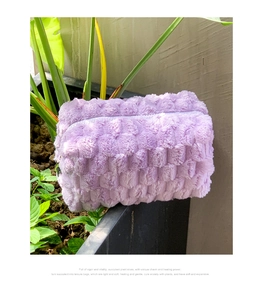 Detail shot of soft purple plush cosmetic bag with wave texture on a green plant pot