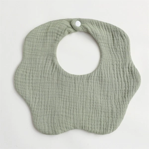 Macro detail of soft sage green flower-shaped muslin cotton baby bib with snap button