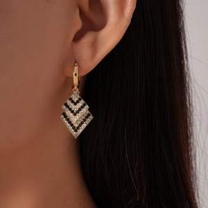 Detailed view of geometric diamond earrings with black and white rhinestones in gold