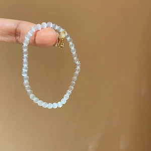 Detailed close-up of opal beaded bracelet featuring a delicate golden butterfly charm