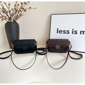Detail view of black and dark coffee leather crossbody bags with metal hardware