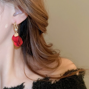 Detail view of red matte petal tassel earrings worn by a model in soft lighting