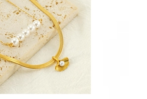 Detail of gold double-layered necklace featuring ginkgo leaf pendant and white pearls