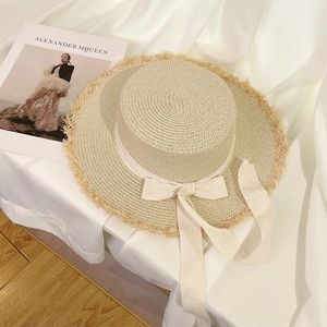 Close-up of a women's straw sun hat with an elegant bow and fringed brim detail