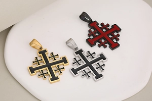 Detailed view of three stainless steel Jerusalem cross pendants in gold, silver, and black