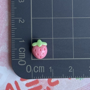 Detailed view of mini resin strawberry charm on measuring mat showing 1cm size