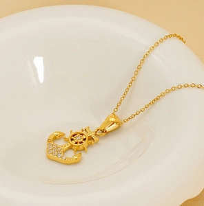 Macro view of gold plated anchor and helm pendant with sparkling zircon inlays