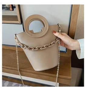 Detail view of khaki bucket bag with round handle and decorative acrylic chain