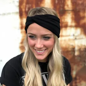 Close-up of a twisted black elastic yoga headband worn by a blonde model on an industrial wall