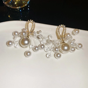 Detail of luxury pearl drop earrings with crystal beads on a white ceramic plate