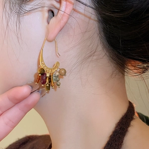 Detailed close-up of 18k gold-plated earrings with colorful beaded stone tassels on model