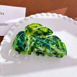Macro view of leaf-shaped acetate hair claw clip with realistic green and yellow texture