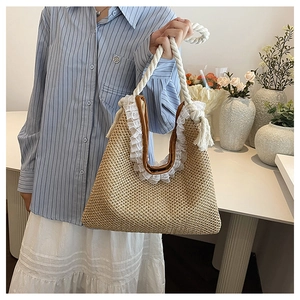 Woven straw handbag with brown leather handles and white lace detail held by a model