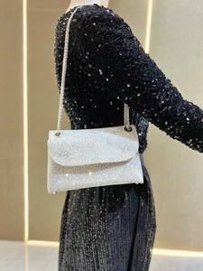 Macro shot of silver rhinestone shoulder bag with metal chain on black dress