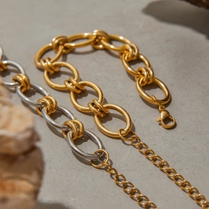 Détail des bracelets à gros maillons dorés et argentés sur pierre avec fermoir mousqueton
