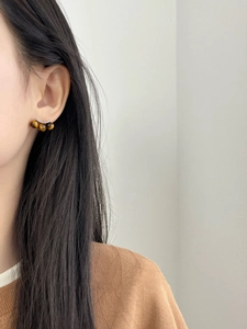 Detailed view of curved tiger eye stone earrings on model side profile in high quality