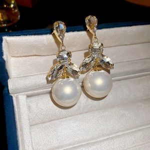Close-up of elegant flower petal earrings with sparkling crystals and a white pearl drop