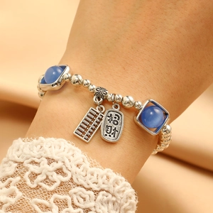 Detail of silver beaded bracelet with blue cat eye stones and abacus charm on wrist