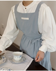 Detail of light blue cotton-linen apron with decorative patch in a home kitchen setting