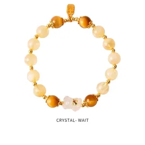 Close-up of strawberry crystal beads with a gold lucky charm and white flower pendant