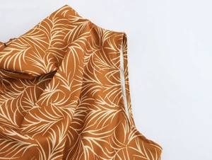 Close-up of lightweight brown fabric featuring detailed beige palm leaf print and texture