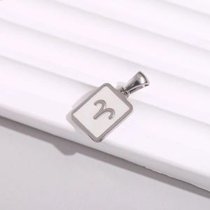 Macro shot of silver Aries zodiac square pendant on textured white rippled surface